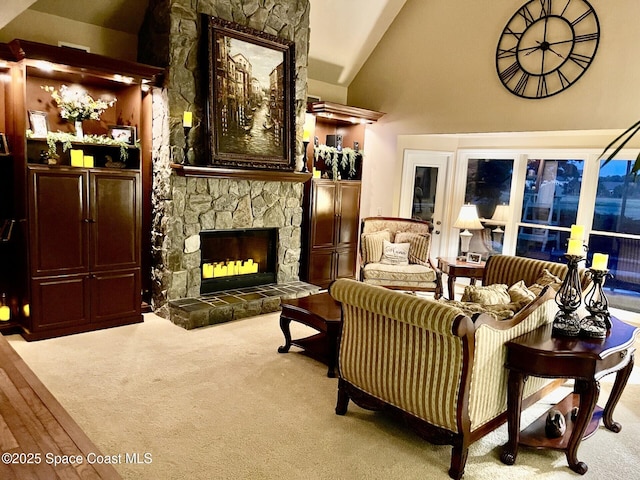 living area with a stone fireplace, carpet floors, and high vaulted ceiling