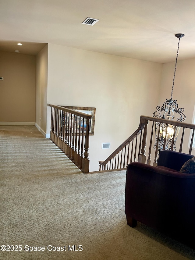 stairway with a chandelier, visible vents, carpet flooring, and baseboards