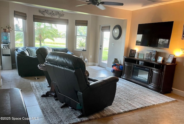 living area featuring a glass covered fireplace, light tile patterned flooring, baseboards, and a wealth of natural light