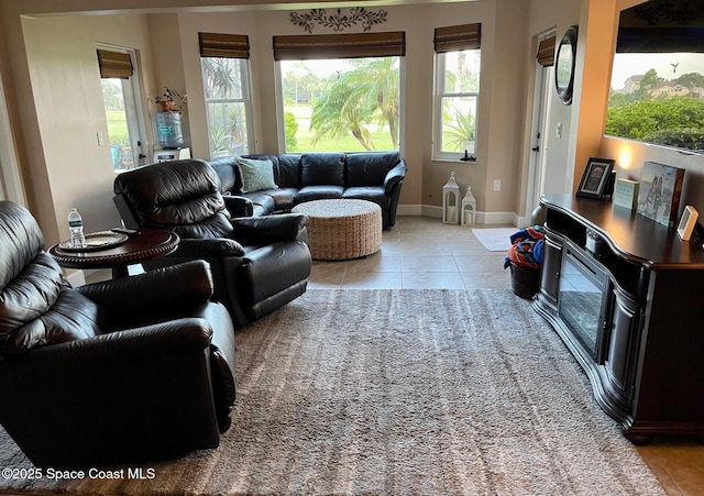 living room featuring light tile patterned floors, baseboards, and a healthy amount of sunlight