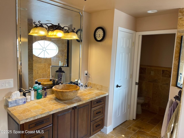 bathroom with toilet, vanity, and tile walls