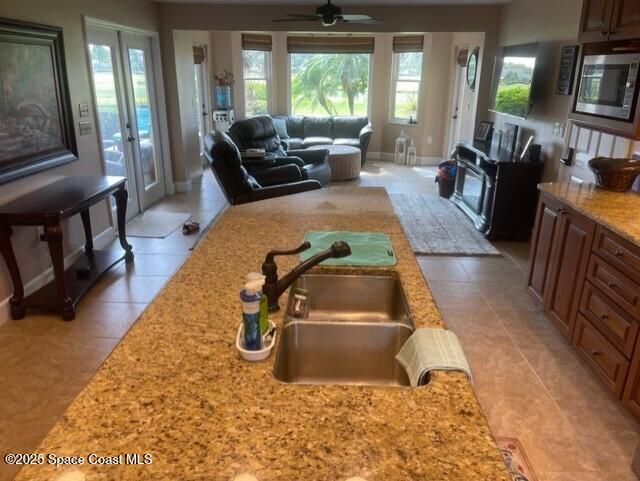 kitchen featuring a wealth of natural light, stainless steel microwave, light tile patterned floors, and a sink