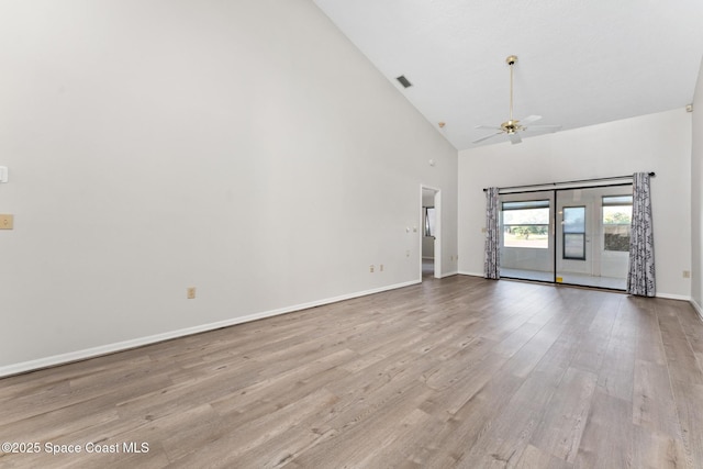 empty room featuring visible vents, high vaulted ceiling, light wood-style flooring, a ceiling fan, and baseboards