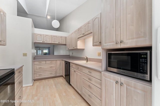 kitchen with light brown cabinets, a sink, black appliances, light countertops, and light wood-type flooring