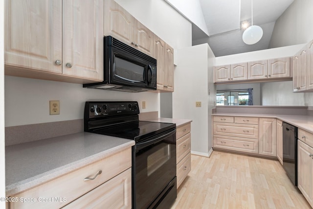 kitchen with light wood finished floors, light brown cabinetry, light countertops, vaulted ceiling, and black appliances