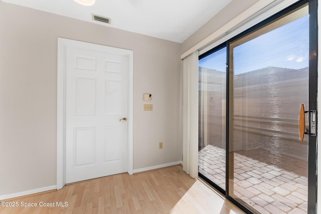 empty room with light wood-style floors, visible vents, and baseboards