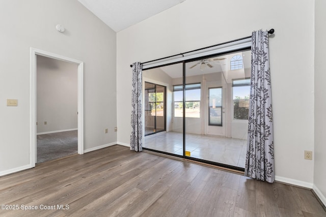 spare room featuring baseboards, wood finished floors, a ceiling fan, and vaulted ceiling