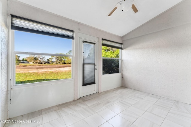 unfurnished sunroom featuring lofted ceiling, a healthy amount of sunlight, and a ceiling fan