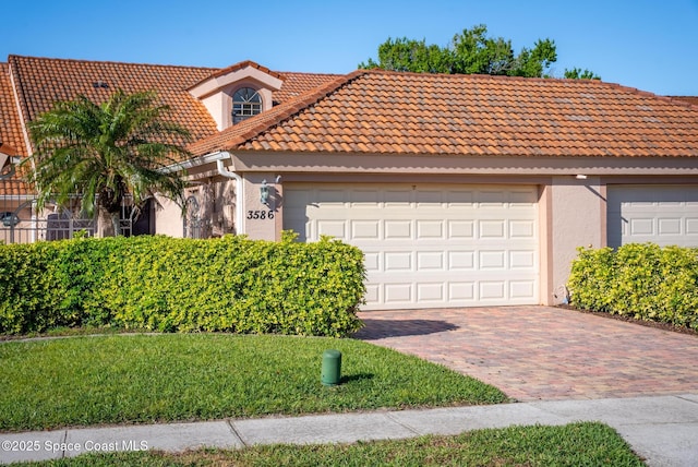 view of front facade with stucco siding, decorative driveway, a garage, and a tiled roof