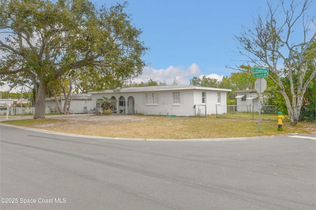 view of front facade with a front lawn, fence, and stucco siding