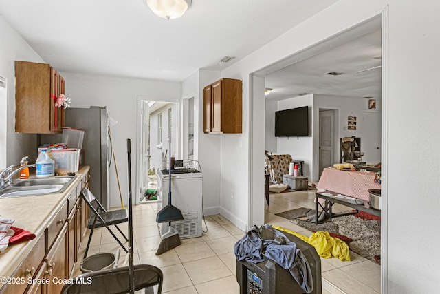 kitchen featuring visible vents, washer / dryer, a sink, light countertops, and brown cabinets