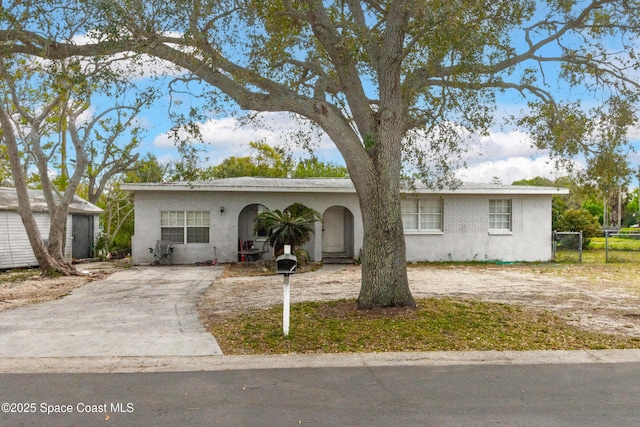 ranch-style house featuring stucco siding, driveway, and fence