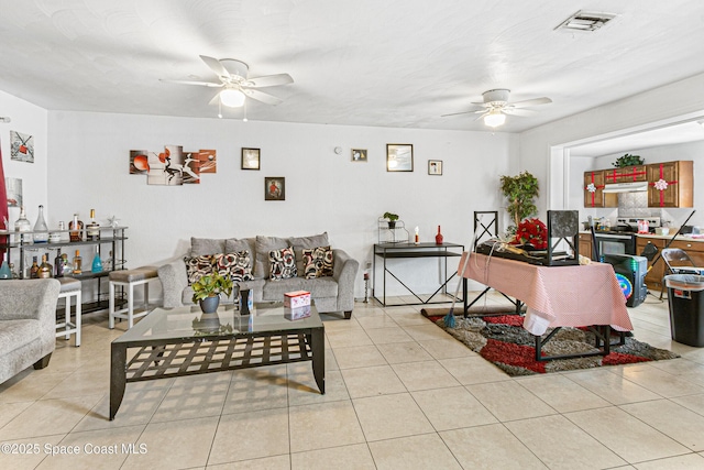 living room featuring light tile patterned floors, visible vents, and a ceiling fan