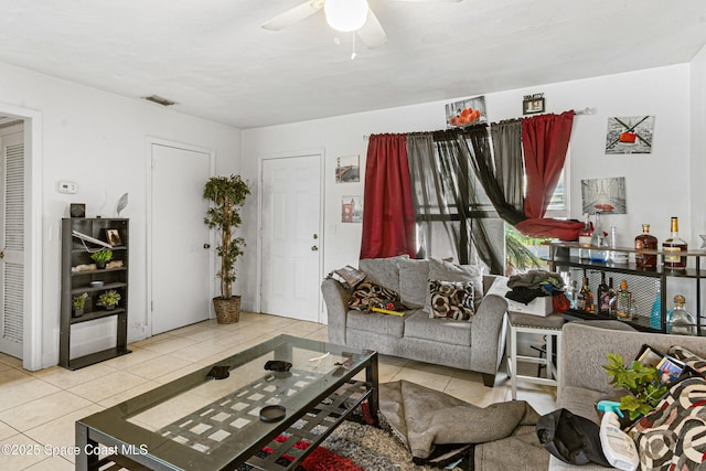 living room with ceiling fan, visible vents, and light tile patterned flooring