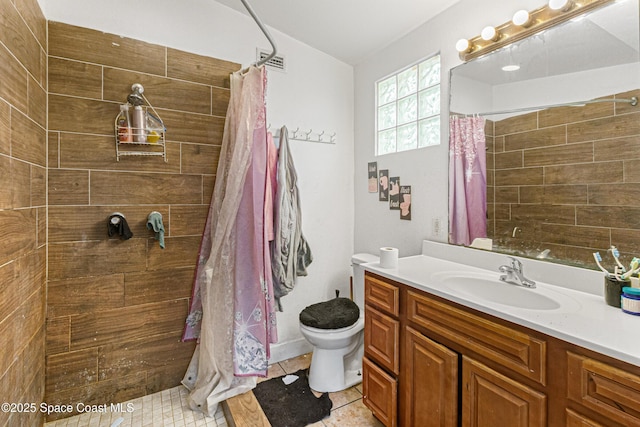 bathroom featuring tile patterned flooring, visible vents, toilet, a tile shower, and vanity