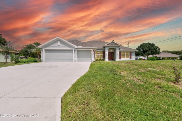 single story home with a garage, a yard, concrete driveway, and stucco siding