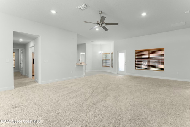 unfurnished living room featuring visible vents, light carpet, ceiling fan with notable chandelier, recessed lighting, and baseboards