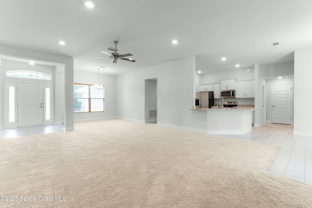 unfurnished living room featuring recessed lighting, light carpet, light tile patterned flooring, and ceiling fan with notable chandelier