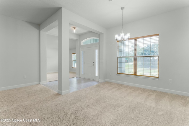 carpeted entrance foyer featuring tile patterned flooring, baseboards, and a chandelier