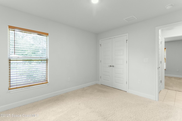 unfurnished bedroom with visible vents, carpet, a closet, and baseboards