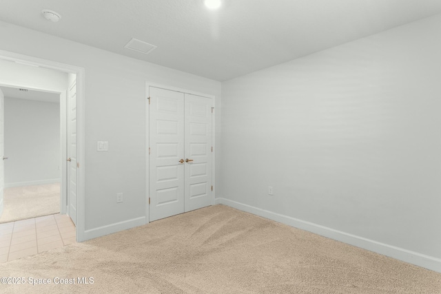 unfurnished bedroom featuring a closet, carpet flooring, tile patterned floors, and baseboards