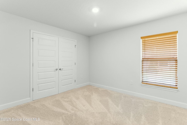 unfurnished bedroom featuring carpet, a closet, and baseboards