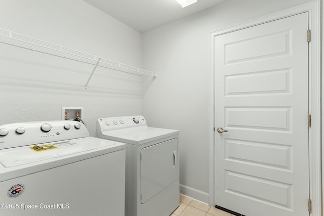 laundry room featuring laundry area, light tile patterned flooring, washing machine and dryer, and baseboards