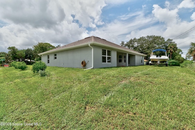 rear view of house with a yard and stucco siding