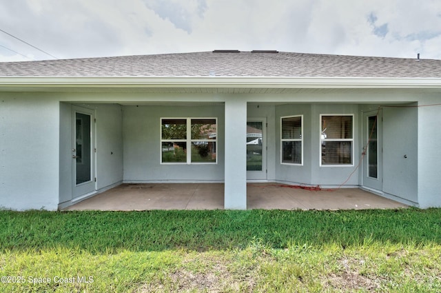 back of property featuring a yard, a patio, roof with shingles, and stucco siding