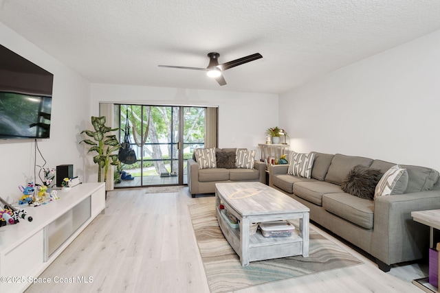 living area with a textured ceiling, ceiling fan, and light wood finished floors