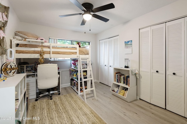 bedroom with two closets, ceiling fan, and wood finished floors