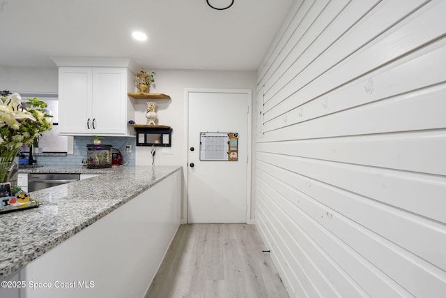 kitchen featuring open shelves, decorative backsplash, white cabinets, stainless steel dishwasher, and light wood-type flooring