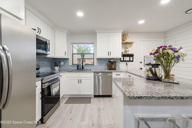 kitchen featuring open shelves, backsplash, light wood-style floors, appliances with stainless steel finishes, and white cabinets