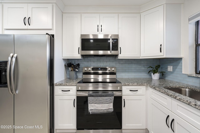 kitchen with tasteful backsplash, white cabinets, and stainless steel appliances