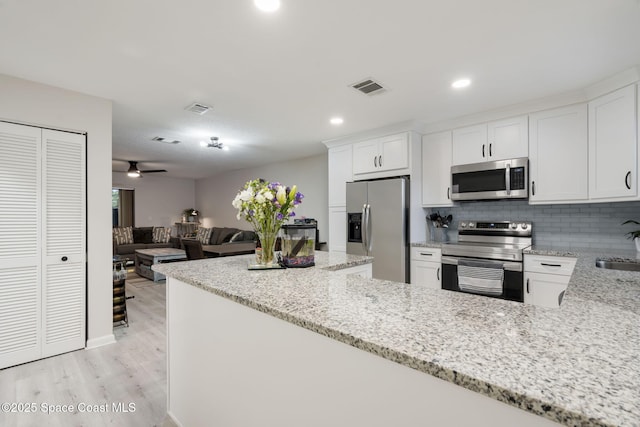 kitchen with light stone counters, stainless steel appliances, visible vents, and white cabinets