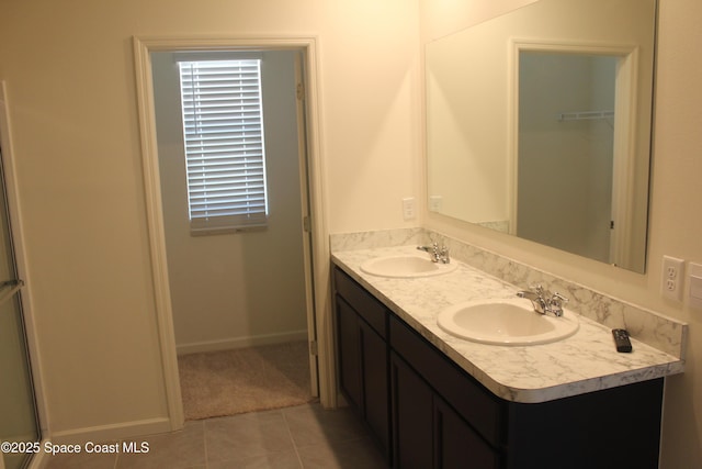 bathroom featuring a sink, baseboards, double vanity, and tile patterned flooring