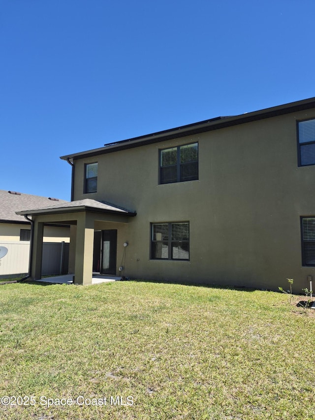 back of house featuring a patio area, stucco siding, and a yard