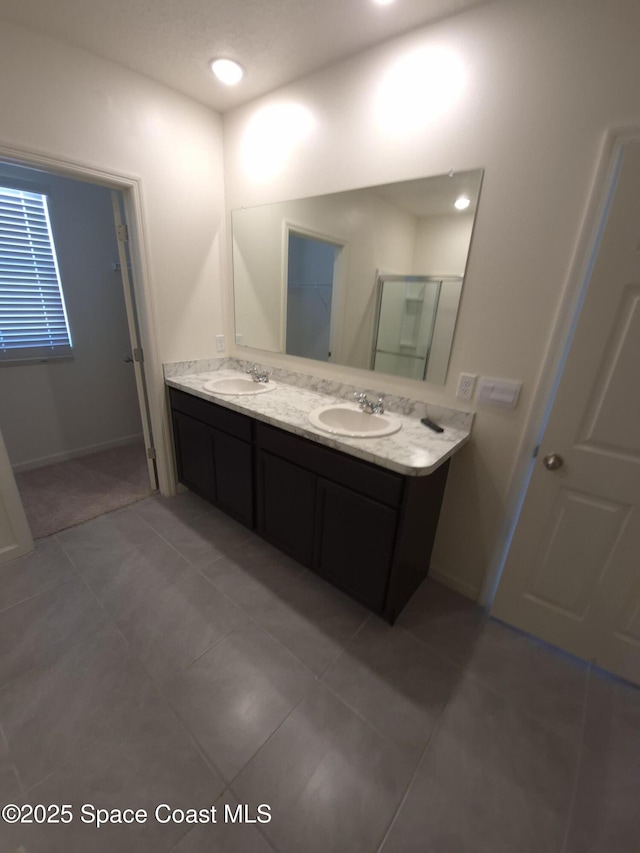 bathroom featuring a sink, baseboards, double vanity, and tile patterned floors