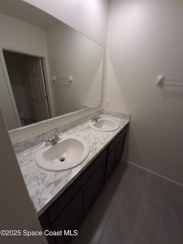 full bath with a sink, toilet, double vanity, and tile patterned flooring