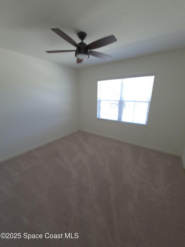 spare room with baseboards, carpet, and a ceiling fan