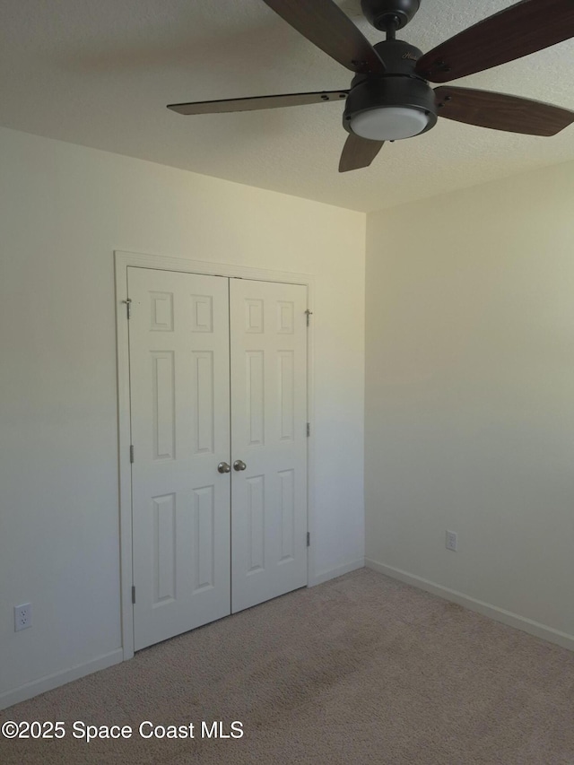 unfurnished bedroom with a closet, baseboards, carpet, and ceiling fan