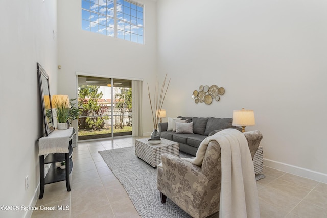 living area with tile patterned flooring, a high ceiling, and baseboards