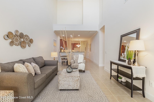 living area featuring a high ceiling, light tile patterned flooring, and baseboards