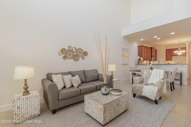 living room with recessed lighting, a high ceiling, an inviting chandelier, light tile patterned flooring, and baseboards