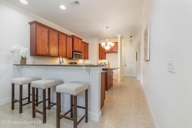 kitchen with a breakfast bar area, visible vents, a peninsula, stainless steel microwave, and a chandelier