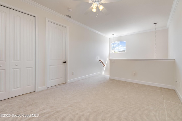 carpeted empty room featuring crown molding, a ceiling fan, and baseboards