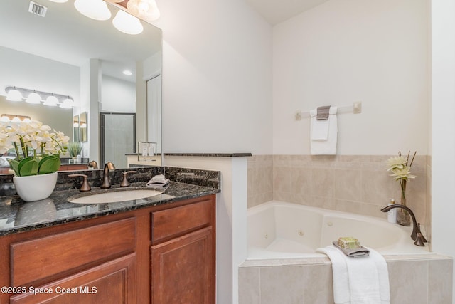 bathroom featuring vanity, a tub with jets, visible vents, and a stall shower