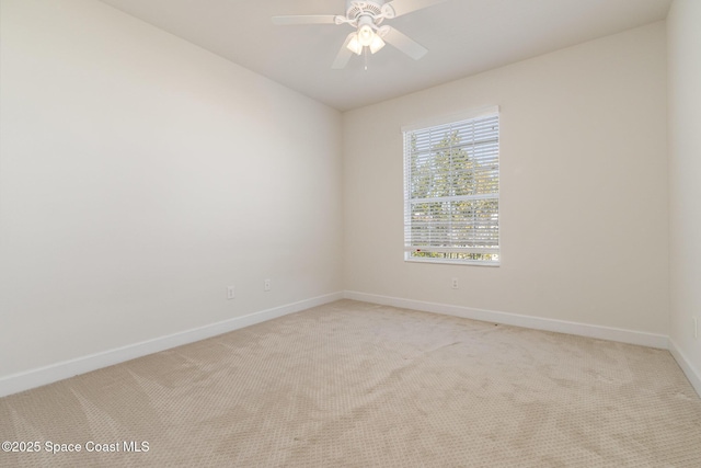 spare room featuring baseboards, light colored carpet, and a ceiling fan