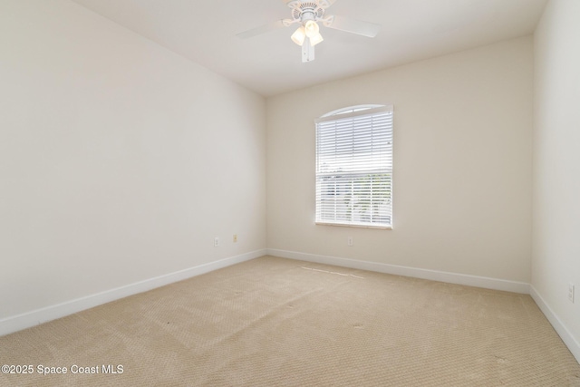 unfurnished room featuring baseboards, light colored carpet, and a ceiling fan