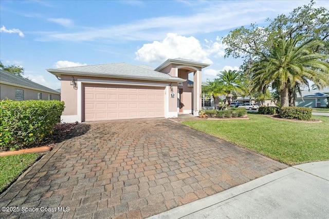 view of front of house with a garage, stucco siding, decorative driveway, and a front lawn